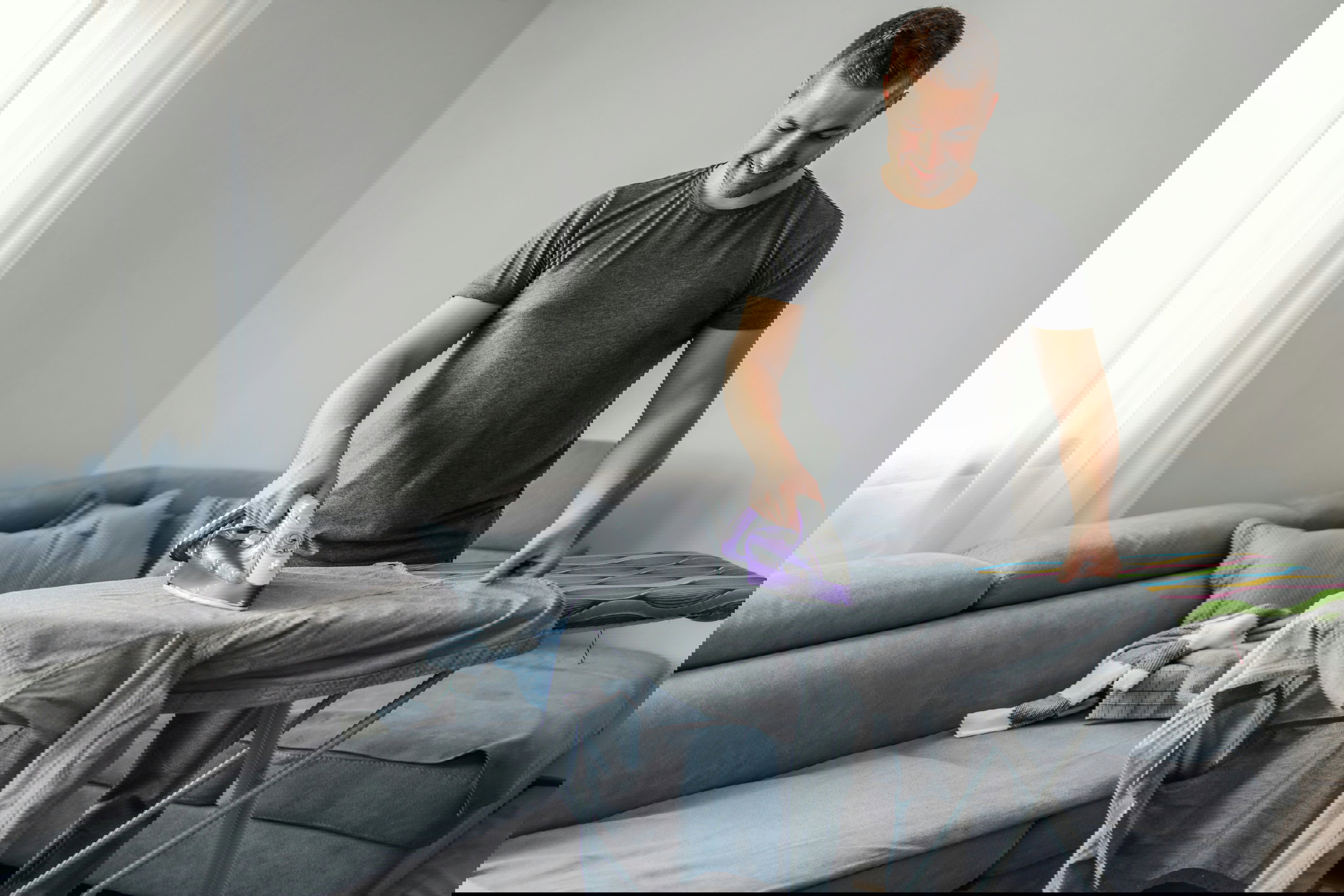 Mann der ein Hemd buegelt